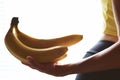 A bunch of bananas in a female hand. Young athletic body of a girl in leggings and a top. Fitness and healthy eating Royalty Free Stock Photo