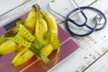 Bunch of bananas with measuring tape on digital body weight scale together with stethoscope