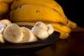 A bunch of bananas and a sliced banana in a bowl on a table Royalty Free Stock Photo