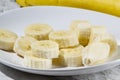 A bunch of bananas and a sliced banana on a plate on a table Royalty Free Stock Photo