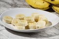 A bunch of bananas and a sliced banana on a plate on a table Royalty Free Stock Photo