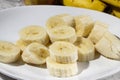 A bunch of bananas and a sliced banana on a plate on a table. Selective focus Royalty Free Stock Photo