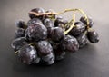 A bunch of black fresh grapes on the black surface. Royalty Free Stock Photo