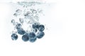 Bunch of blueberries splashing into crystal clear water and sinking under water with air bubbles Royalty Free Stock Photo