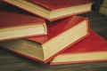 A bunch of books with a scarlet cover on a wooden table. Red books are thrown on the table. books with a red cover lie