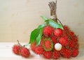 Bunch of Bright Color Red and Green Fresh Ripe Rambutan Whole Fruits and Peeled Isolated on Wooden Table