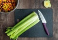 Bunch of celery washed and ready to chop on a black cutting board with chef knife Royalty Free Stock Photo