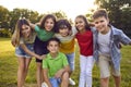 Bunch of cheerful little friends hugging and posing for a group photo in the park