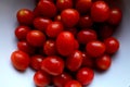 A Bunch of Cherry Plum Red Shiny Tomatoes in a White Ceramic Bowl on a Wooden Background Royalty Free Stock Photo