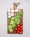 Bunch of cherry tomatoes, spinach and mushrooms on a cutting board on wooden rustic background top view close up Royalty Free Stock Photo