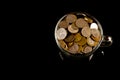 Bunch of coins in a glass cup over black background Royalty Free Stock Photo