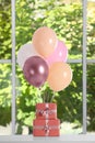 Bunch of color balloons and beautifully wrapped gift boxes on white table near window Royalty Free Stock Photo