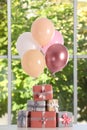 Bunch of color balloons and beautifully wrapped gift boxes on white table near window Royalty Free Stock Photo