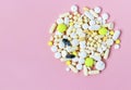 A bunch of colorful pills on a pink background. Copyspace for text. Epidemic, pain relievers, health care, medical pills