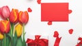 Bunch of colorful tulips flowers and gift box with red envelope on white table background. Easter day, Mother day, Valentines day Royalty Free Stock Photo