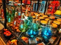 Bunch of colourful glass bulbs clustered together on a glass table in a home decoration shop .