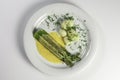 Bunch of cooked asparagus on white plate with hollandaise sauce, potatoes and dill