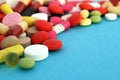 A bunch of different bright pills and capsules lie on a blue background.