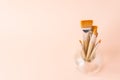 Bunch of different types and sizes of paint brushes in glass jar on light peachy pink background. Arts creativity painting drawing