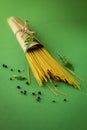 Bunch of dry spaghetti pasta with fresh spices, herbs and peppers isolated on deep green studio background Royalty Free Stock Photo