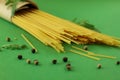 Bunch of dry spaghetti pasta with fresh spices, herbs and peppers isolated on deep green studio background Royalty Free Stock Photo