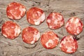 Bunch of Eight Pork Salami Slices Set On Rustic Wooden Chipboard Rough Grunge Surface