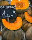 Bunch of Fairytale pumpkins whole cut in wedges and halved at farmers market with chalkboard price tags in Spanish. Thanksgiving