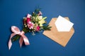 Bunch of flowers kraft paper envelope with blank white letter with copy space lay on blue background Royalty Free Stock Photo