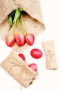 Bunch of flowers near pink Easter eggs in sackcloth bag. Royalty Free Stock Photo
