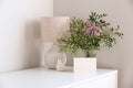 Bunch of flowers in vase, scandinavian style table lamp, bird , blank greeting card mockup on white table. Cozy home living room Royalty Free Stock Photo