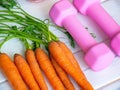 Bunch of fresh carrot with dumbbells . Concept carrot for health, normalization of arterial pressure, sport. Royalty Free Stock Photo