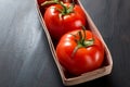 Red organic tomatoes in a basket on grey old kitchen table Royalty Free Stock Photo