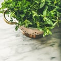 Bunch of fresh garden herbs in brass colander, square crop