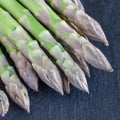 Bunch of fresh green asparagus on dark slate background, square format