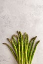A bundle of fresh green asparagus on a grey background, copy space, vertical