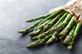 Bunch of fresh green asparagus sprouts in craft paper grocery bag on stone table. Healthy and diet food. Royalty Free Stock Photo