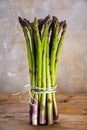 Bunch of fresh green asparagus standing on a rustic wooden table Royalty Free Stock Photo