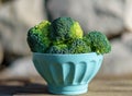 Bunch of fresh green broccoli in bowl on wooden table close up on the background of a stone wall. Royalty Free Stock Photo