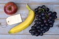 Bunch of fresh organic black grapes, banana, red apple, and a blank label tag on a wooden table Royalty Free Stock Photo