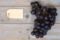 Bunch of fresh organic black grapes and a blank label tag on a wooden table Royalty Free Stock Photo