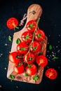 A bunch of fresh organic cherry tomatoes with sea salt and basil in olive cutting board Royalty Free Stock Photo