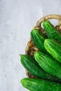 Bunch of Fresh Organic Cucumbers in Wicker Basket on Grey Metal Cement Stone Background. Summer Vitamins Healthy Diet