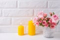 Bunch of fresh pink roses flowers in pot and two yellow candles Royalty Free Stock Photo