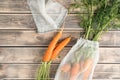 Bunch of fresh ripe carrots with long green haulm on faded wooden table, top view. Unpacking vegetables from transparent