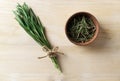 A bunch of fresh rosemary tied with a jute and dry in a wood piae on a wood table. Rustic style.