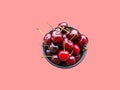 Bunch of freshly picked red glossy sweet cherries in mug on pink background. Summer berries fruits healthy plant based diet
