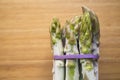 Bunch of frozen wild asparagus tied with rubber tape from ecological agricuture over wooden background