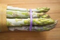 Bunch of frozen wild asparagus tied with rubber tape from ecological agricuture over wooden background
