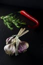 A bunch of garlic on a black background next to the rormarin and chili peppers Royalty Free Stock Photo