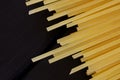 A bunch of golden spaghetti lies on a black wooden background. Minimalism